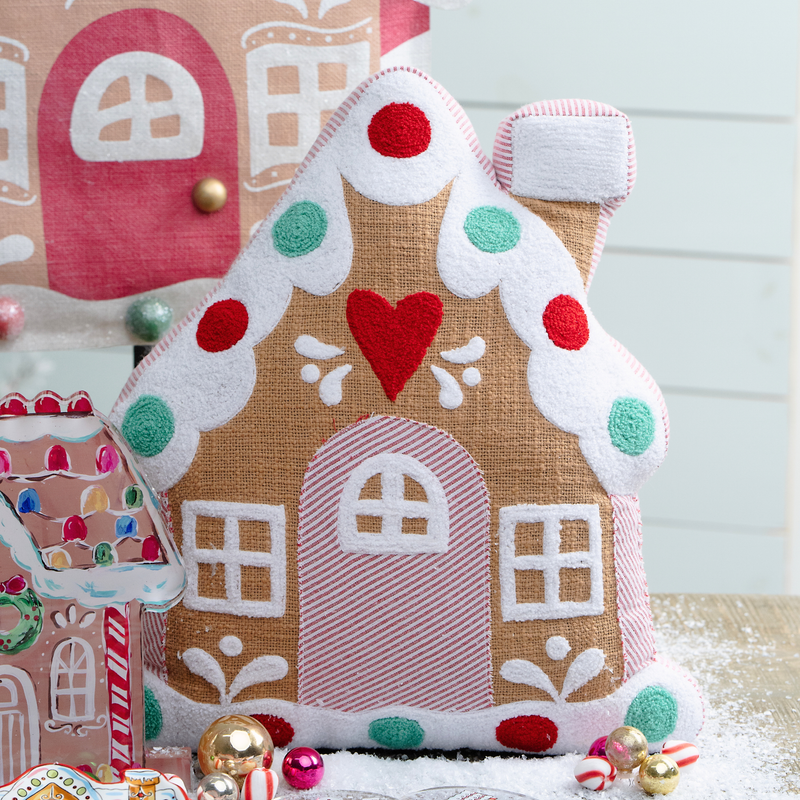 Decorative gingerbread house pillow with colorful details on a light blue background