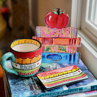 Colorful acrylic sculpture of stacked books with an apple on top 