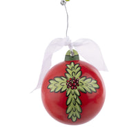 A red glass ball Christmas ornament with a detailed green cross design and a white ribbon at the top.