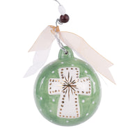 Green ceramic ornament with a white cross design on a white background