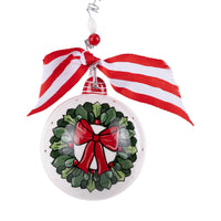 Christmas ornament with a wreath and red bow design, hanging from a red and white striped ribbon.