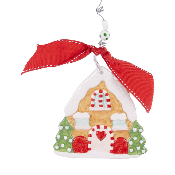 Decorative gingerbread house ornament with a red ribbon on a white background