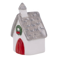 Small ceramic house-shaped charcuterie topper with a red door and green wreath on a white background