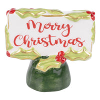 Decorative figurine with 'Merry Christmas' text and holly design on a white background