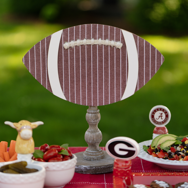 Football-shaped centerpiece on a table with food and decorative items outdoors