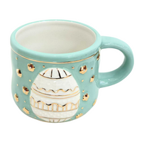 Teal mug with decorative egg design on a white background