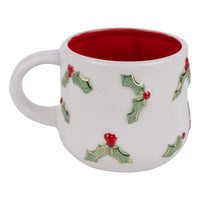 White mug with holly design and red interior on a white background