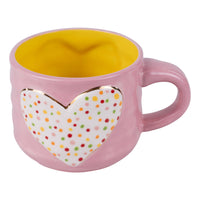 Pink mug with a heart-shaped polka dot design on a white background