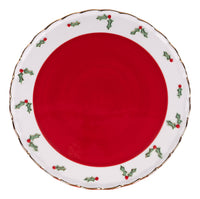 Red cake stand with decorative white rim featuring holly designs on a white background