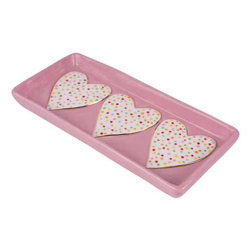 Three heart-shaped cookies with polka dot pattern on a pink tray