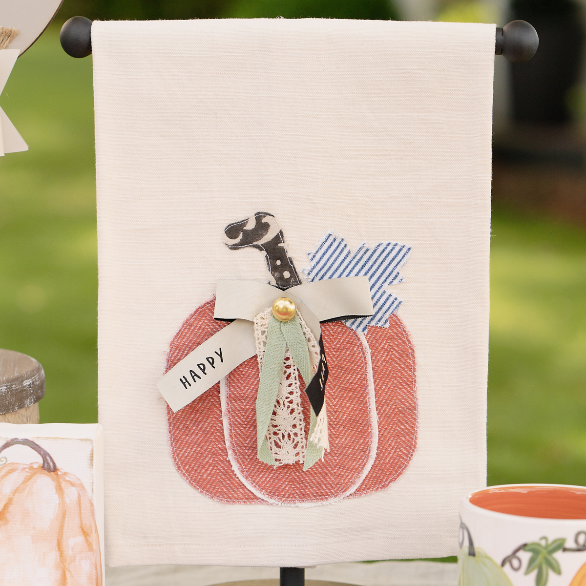 Decorative towel with a pumpkin design and 'Happy' banner, outdoors.