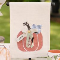 Decorative towel with a pumpkin design and 'Happy' banner, outdoors.