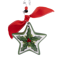 A star-shaped Christmas ornament with green holly leaves and red berries, tied with a red ribbon at the top.