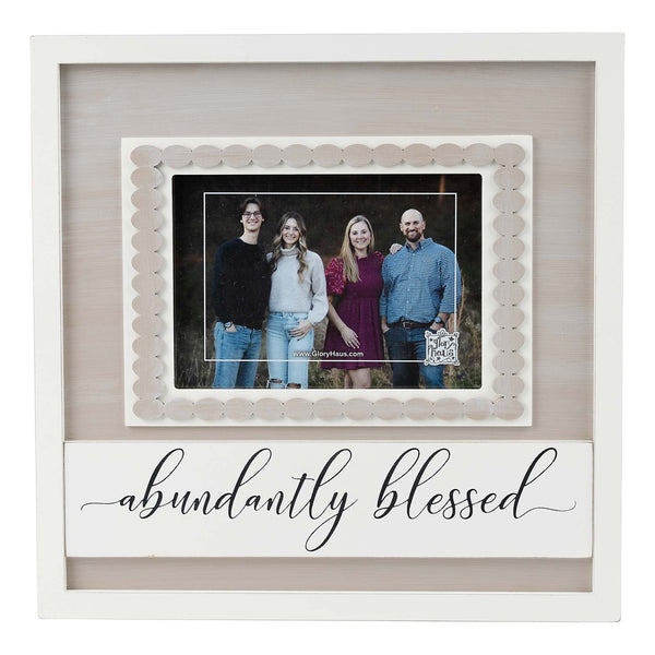 A photo frame with a scalloped edge and the text 'abundantly blessed' displayed on the front, containing a picture of a family.