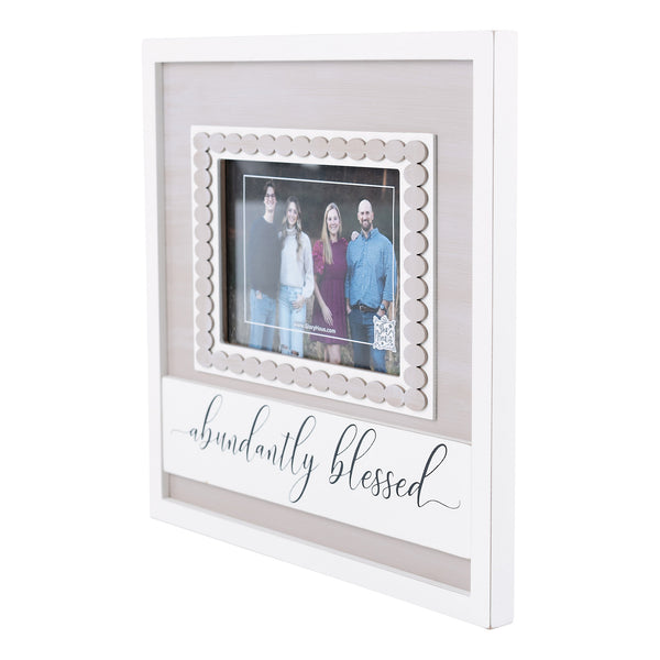 A photo frame with a scalloped edge and the text 'abundantly blessed' displayed on the front, containing a picture of a family.