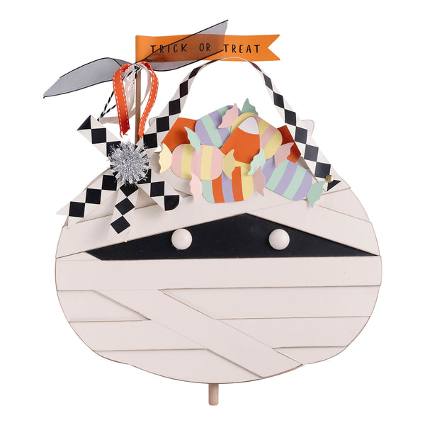 Halloween-themed candy holder shaped like a mummy with checkered bandages and a 'Trick or Treat' banner.