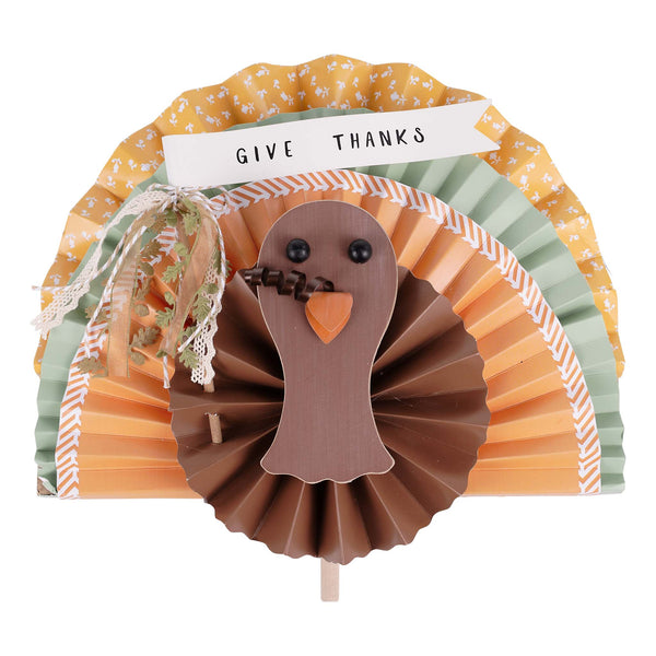 Decorative paper turkey with 'Give Thanks' banner on a white background