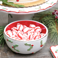 Decorative bowl with red interior and white exterior featuring holly designs.
