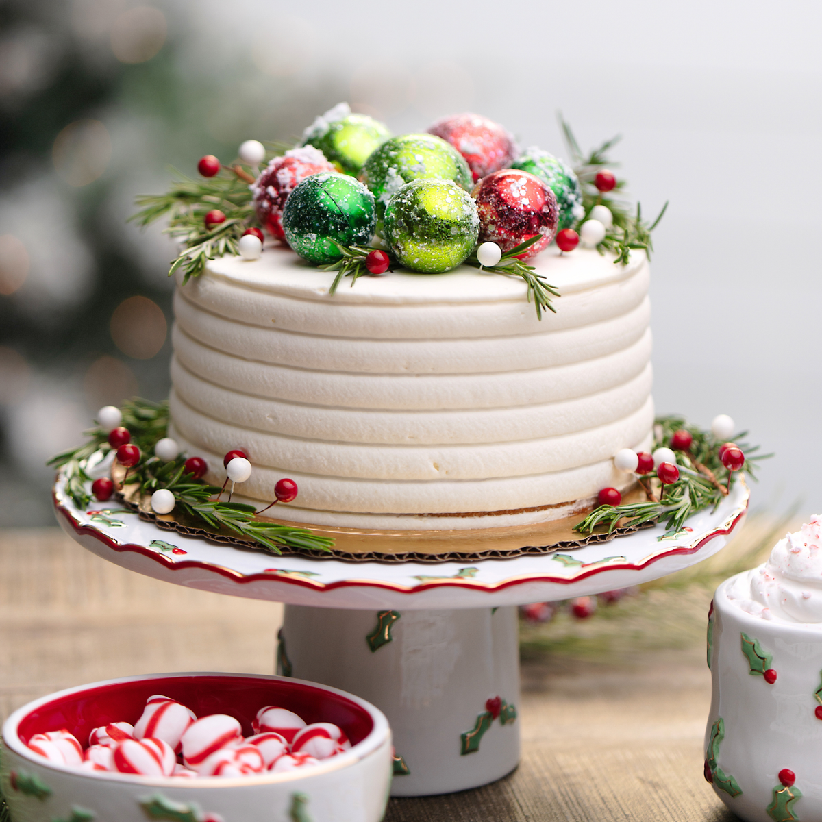 Decorative Christmas cake with candy decorations on a stand, surrounded by festive elements.