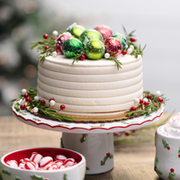 Decorative Christmas cake with candy decorations on a stand, surrounded by festive elements.