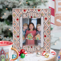 Decorative photo frame with a Christmas theme, featuring children holding gingerbread houses, on a festive background.