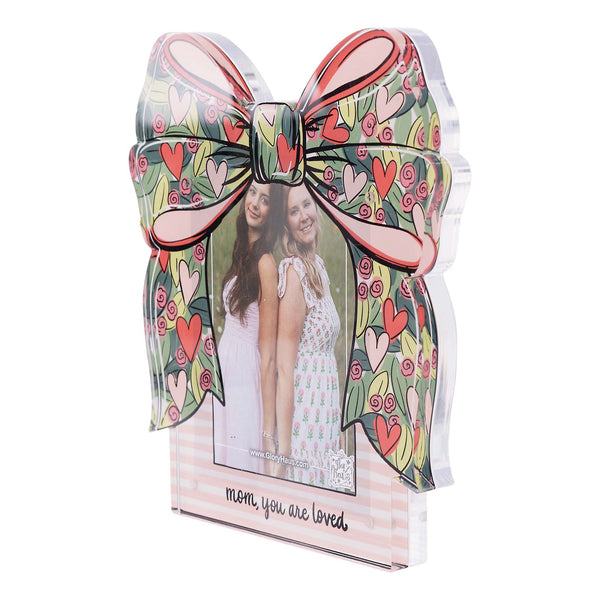 Decorative photo frame with a large bow design and a photo of two women inside, on a white background.
