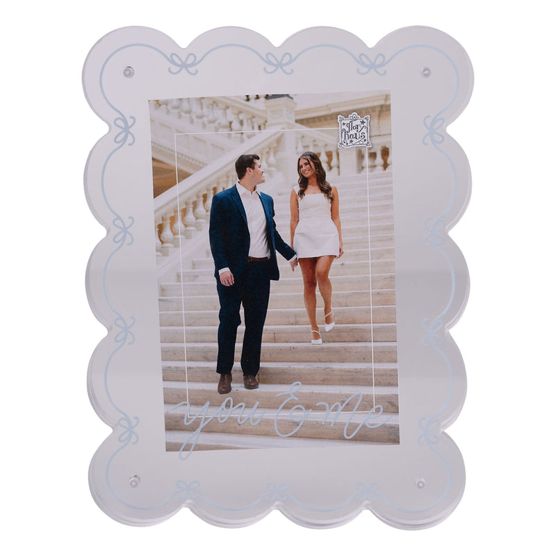 Decorative photo frame with scalloped edges holding a picture of a couple on stairs.