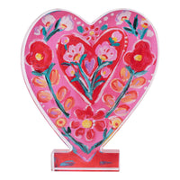 Heart-shaped decorative item with floral design on a pink background