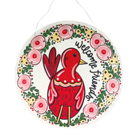 Decorative round sign with a red bird illustration and floral wreath, featuring the text 'welcome friend'.